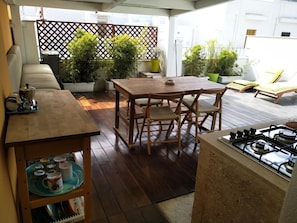 A patio area with a wooden table and chairs, a gas stove, and potted plants. - Dimora Dioniso (Polignano a Mare)