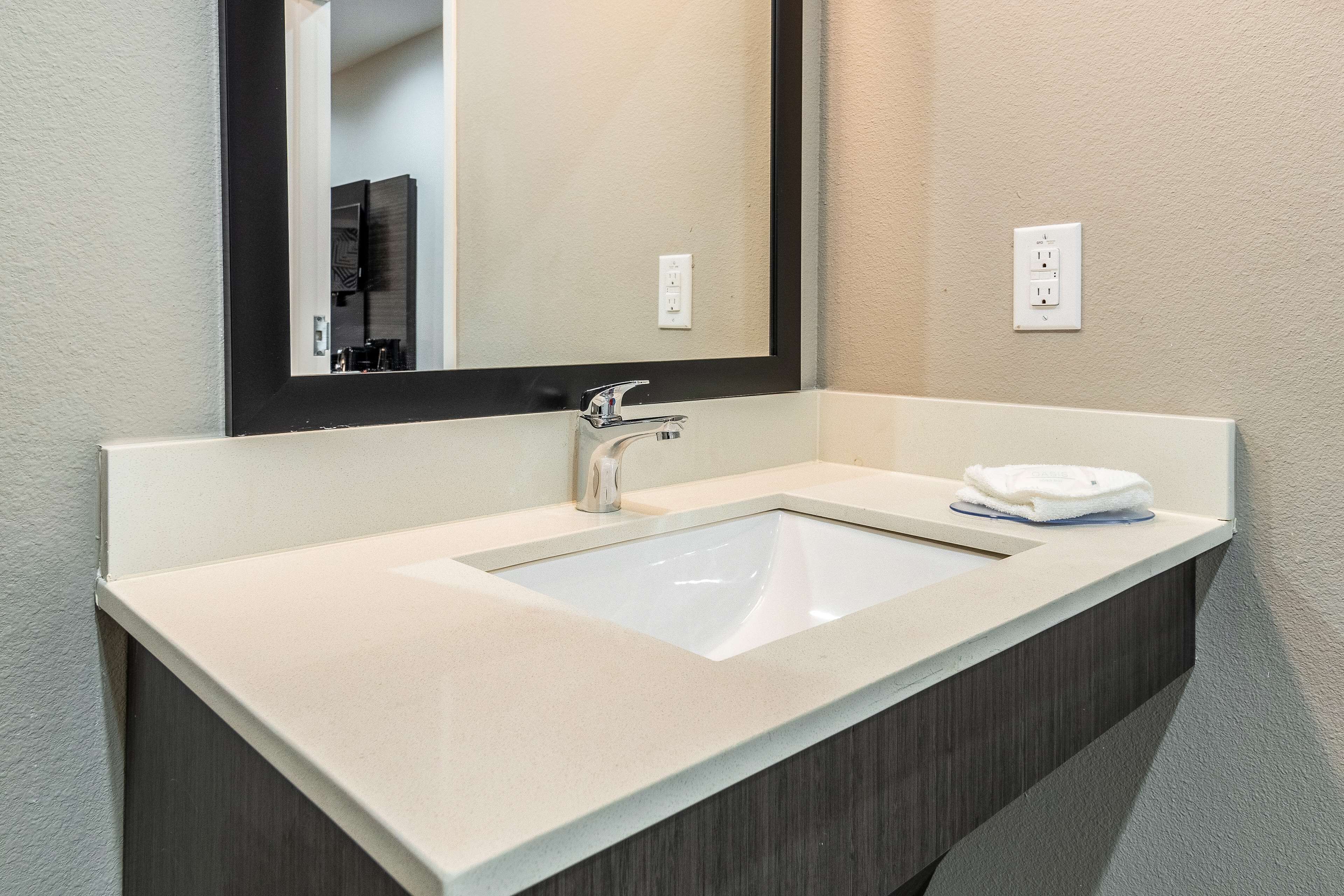 Une salle de bain avec un lavabo blanc, un miroir et une serviette posée sur le comptoir.