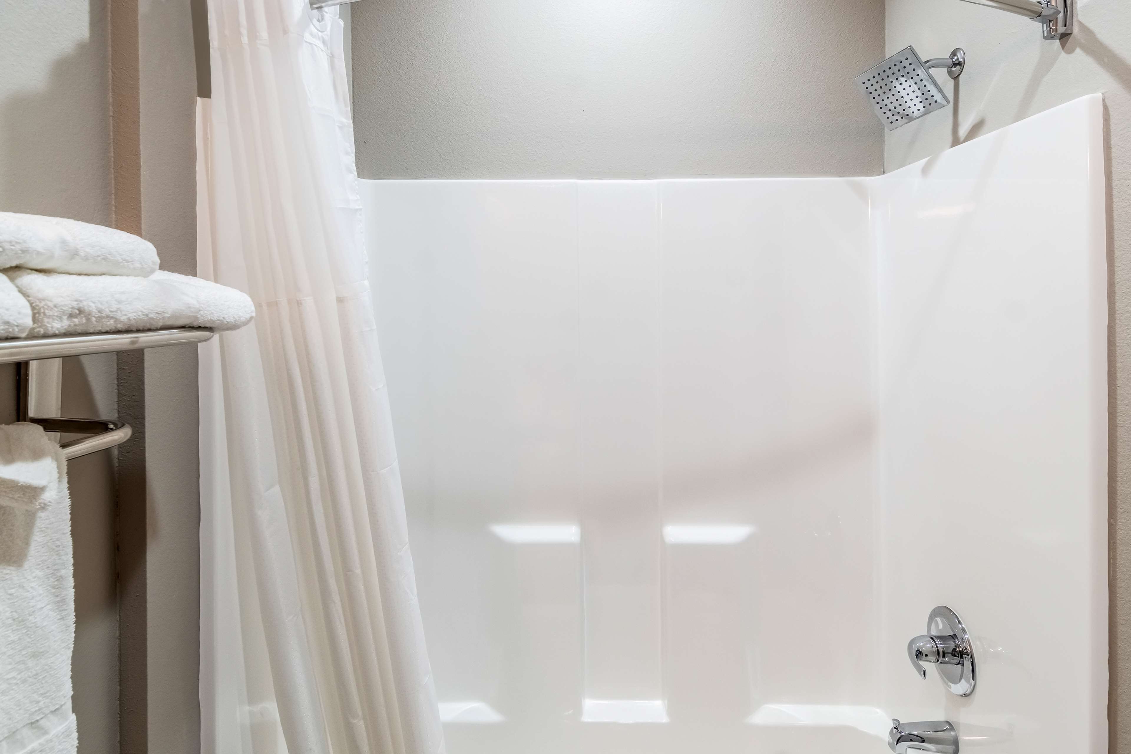A bathroom with a shower, a sink, and a towel rack.