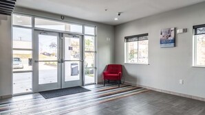 Un hall d’hôtel avec un fauteuil rouge, de grandes portes vitrées et un tapis à motifs.