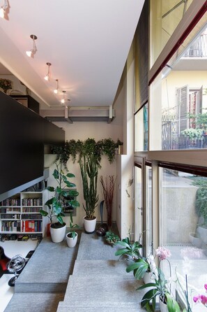 A modern interior with a staircase, potted plants, and a view through large windows. - Luxury Villa Urbana with Private Garden in center town (Torino)