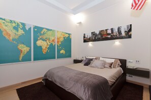 A modern hotel room with a large bed, a world map on the wall, and a cityscape picture. - Luxury Villa Urbana with Private Garden in center town (Torino)