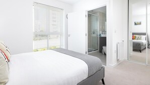 A modern bedroom with a bed, a walk-in closet, and a bathroom.