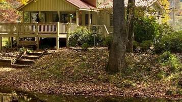 A wooden cabin with a porch and a small dock extending into a pond.