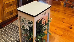 Une cuisine avec des meubles de rangement en bois, une cuisinière et une petite table agrémentée d’une plante.