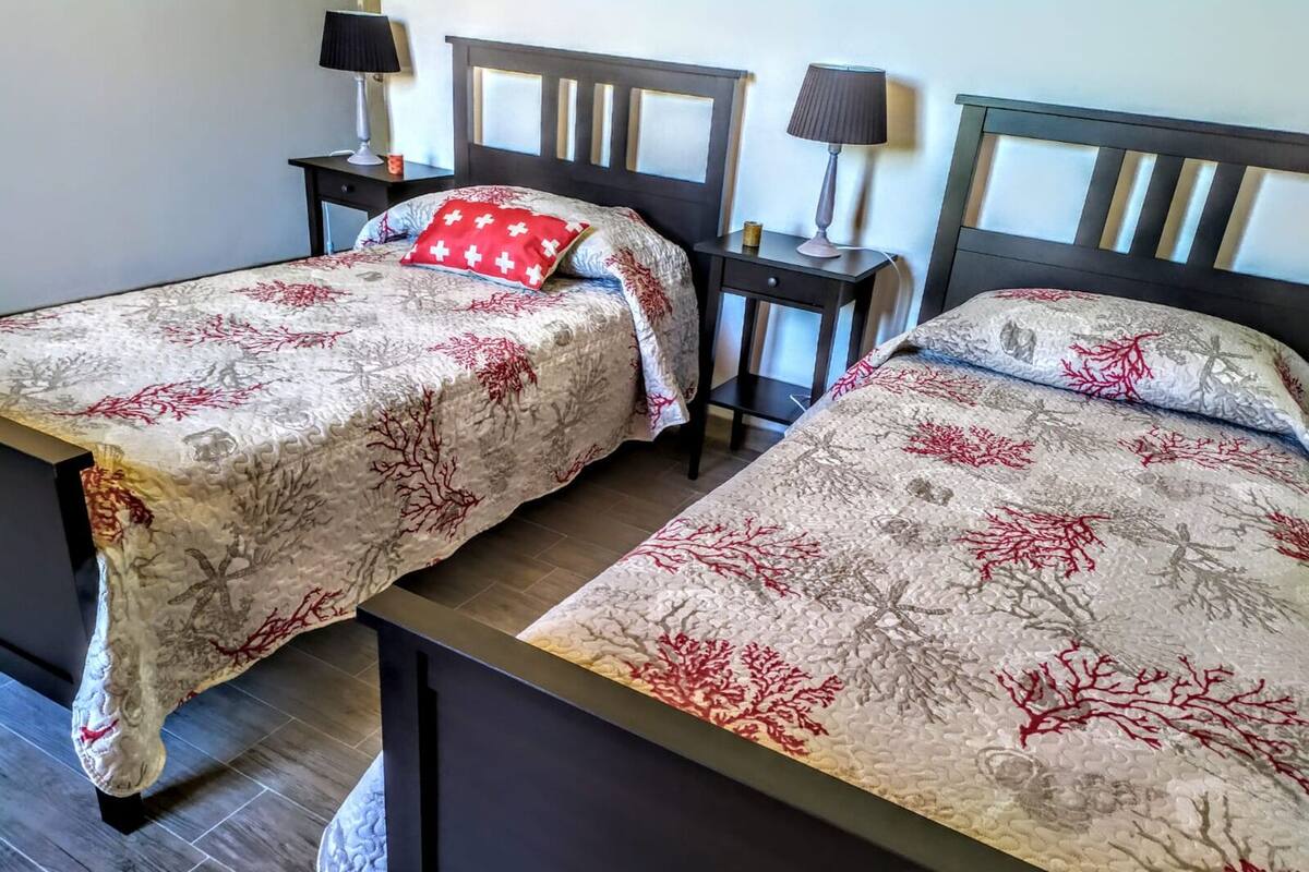 Una habitación con dos camas, cada una con cabecera y mesitas de noche.
