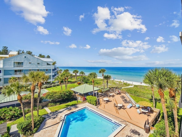 A resort with a swimming pool, beach view, and palm trees. - Beachfront Bliss at Driftwood Sands. 3 bedrm on the Gulf w/ Pool, Private Access (Indian Rocks Beach)