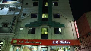 Un edificio con dos escaparates, uno que dice "S.R. Residency" y el otro "S.R. Bake".