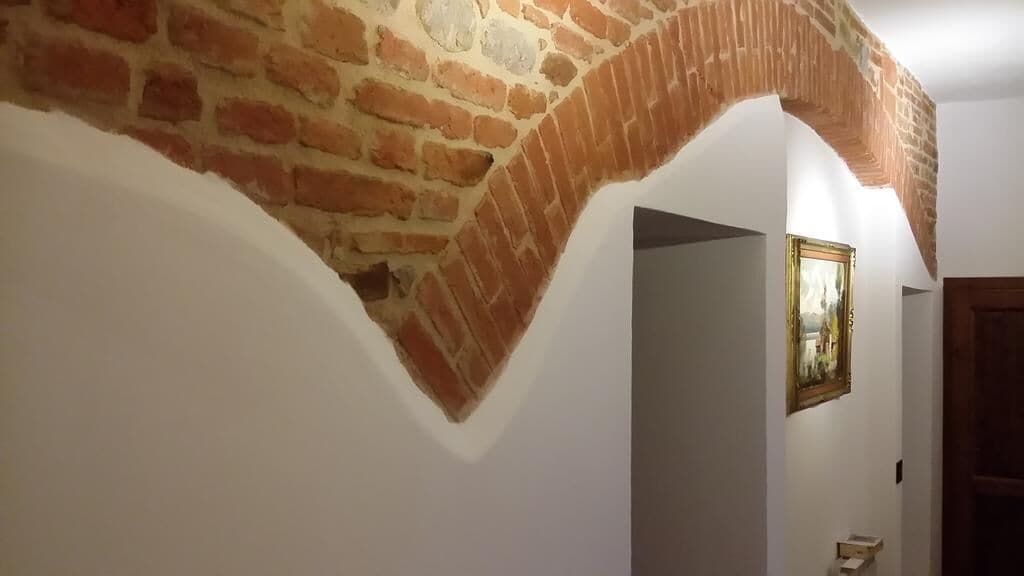 A hallway with a brick archway and a framed painting on the wall.