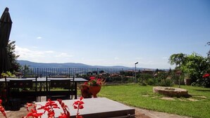Un espace extérieur aménagé en terrasse, avec une table et des chaises, un chemin en pierre et une vue sur les montagnes lointaines.