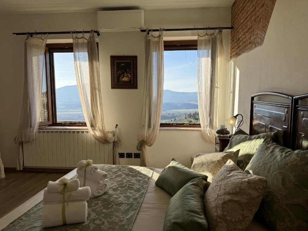Un dormitorio con cama, almohadas, una mesita de noche y una ventana con cortinas.