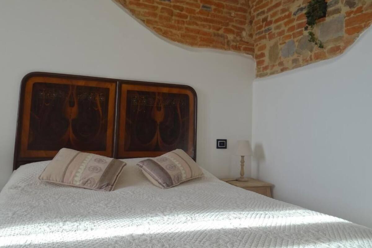 Ein Schlafzimmer mit Ziegeldecke, einem Holzkopfteil und einem Nachttisch mit Lampe.