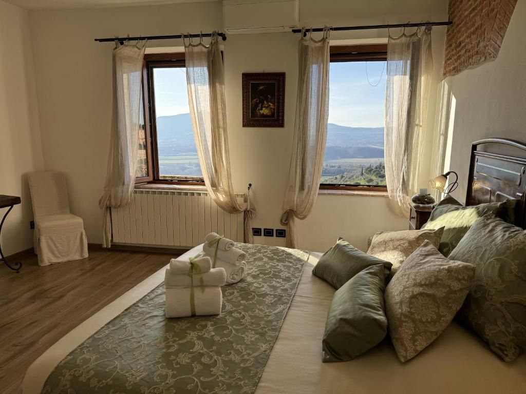 A bedroom with a bed, a chair, a window with curtains, and a view of the landscape.
