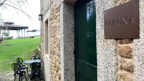 A stone building with a green door and a sign reading "CURUXA". - Stone house restored in the middle of nature (Lage - A Coruña)