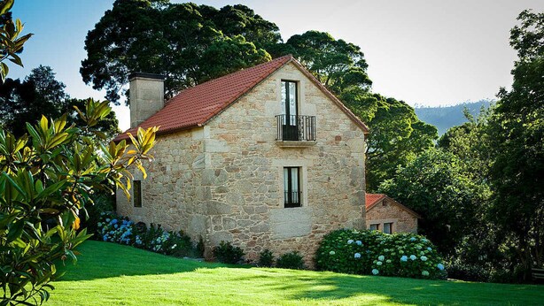 A stone house with a red roof, a balcony, and a well-maintained garden. - Stone house restored in the middle of nature (Lage - A Coruña)