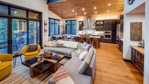 Ein moderner, offener Wohn- und Essbereich mit großzügigem Sofa, Esstisch und Küche im Hintergrund.