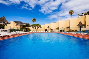 Una piscina con sillas de descanso y palmeras.