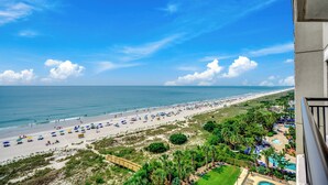 Uma praia com guarda-sóis e área de piscina.