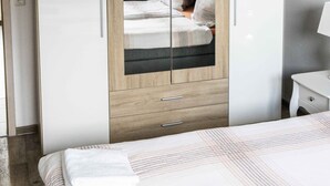A modern bedroom with a bed, a wardrobe, and a nightstand. - Ferienwohnung Anke-Apartement 5a (Heinsberg)