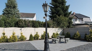 A paved courtyard with a stone wall, a street lamp, and a bench. - Ferienwohnung Anke-Apartement 5a (Heinsberg)