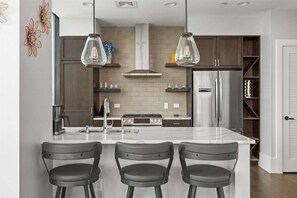 Une cuisine moderne dotée d’un îlot central, de luminaires suspendus et d’une cuisinière intégrée.