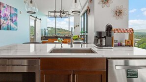A modern kitchen with a large island, stainless steel appliances, and a view of the outdoors. - Endless Sunset Retreat | Arras Vacation Rentals (Asheville)