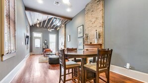 Un espace repas avec un mur en briques, un plancher en bois et une table entourée de chaises.