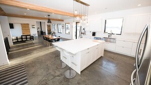 Een moderne keuken met een groot kookeiland, witte kastjes en een hangende lamp.
