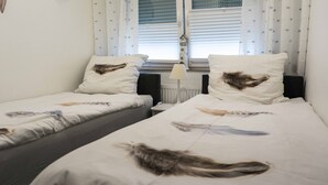 A twin room with two single beds, each with a pillow featuring a feather design. - Ferienwohnung Anke-Apartement 5d (Heinsberg)