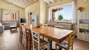 Un espace repas comprenant une table et des chaises en bois, un téléviseur et une vue sur l’extérieur.