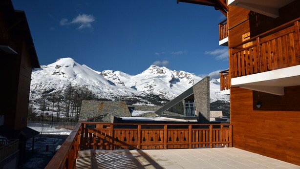 Un edificio de madera con balcón que da a montañas nevadas.