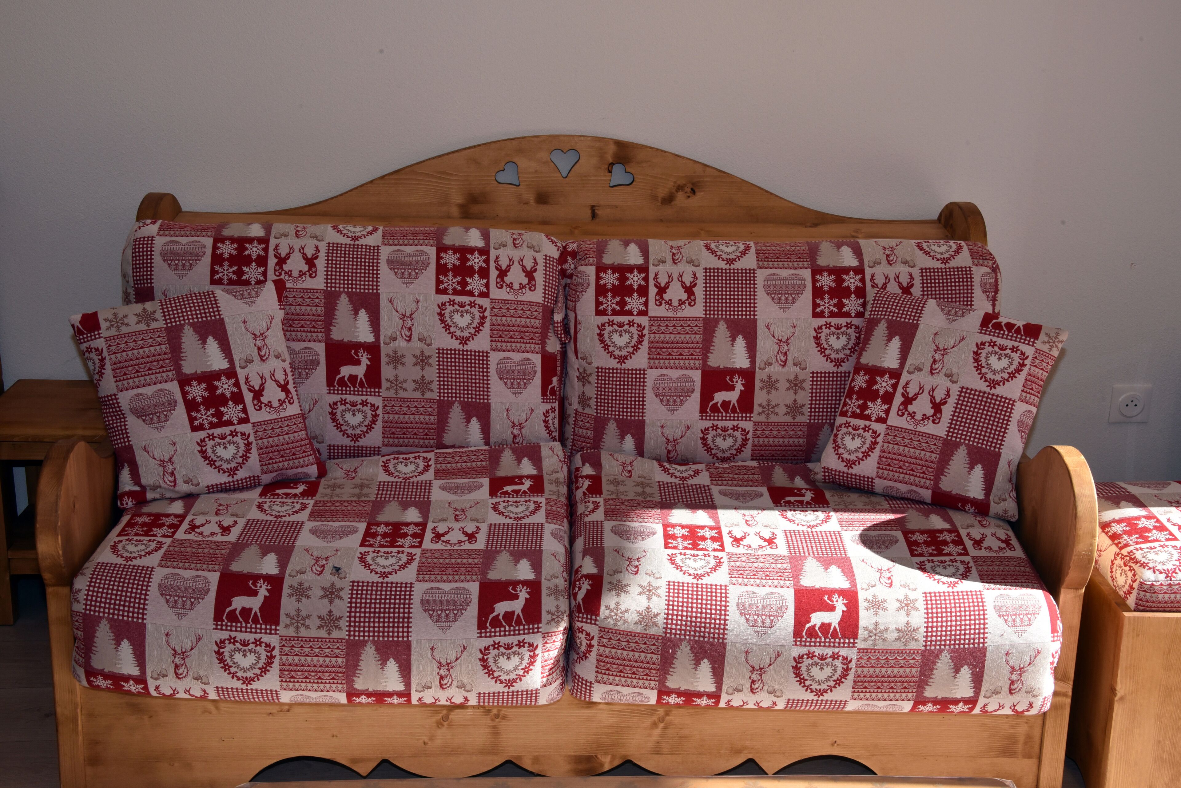 A wooden sofa with a red and white checkered cushion pattern.