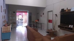 A living room with a sofa, a TV, and a dining area with a table and chairs. - Prad Residence (Recife)