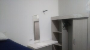 A bedroom with a bed, a bedside table, a mirror, and a wardrobe. - Prad Residence (Recife)
