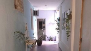 A narrow hallway with a tiled floor, a chair, and a potted plant. - Prad Residence (Recife)