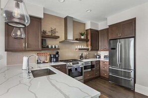 A modern kitchen with stainless steel appliances, a marble countertop, and wooden cabinets.