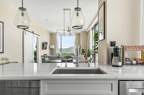 Een moderne keuken met een centraal eiland, roestvrijstalen apparatuur en hanglampen.