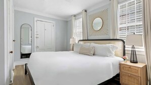 Une chambre à coucher bien aménagée, avec un grand lit, une table de chevet avec une lampe, un miroir et un élément décoratif mural en forme de soleil.