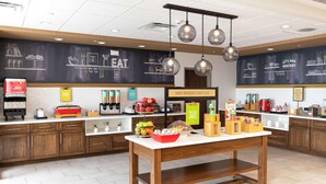 Ein Frühstücksbuffet mit einer Kreidetafel-Speisekarte, einem Saftspender und einer Auswahl an Frühstücksangeboten.