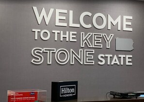 Pared con el texto 'WELCOME TO THE KEY STONE STATE' y un cartel de Hilton Honors.