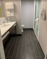 Un baño moderno con lavamanos blanco, inodoro y cabina de ducha de vidrio.