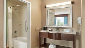 Une salle de bain avec une baignoire, un meuble-lavabo avec un miroir et un porte-serviettes.