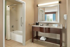 A bathroom with a bathtub, a vanity with a mirror, and a towel rack. - Hampton Inn & Suites Pittsburgh New Stanton (New Stanton)