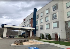 Hotel de vários andares com entrada coberta, estacionamento e vaga para pessoas com deficiência.