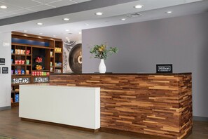 A hotel reception desk with a wooden design, a white counter, and a sign indicating it's a Hilton Honors location. - Hampton Inn & Suites Pittsburgh New Stanton (New Stanton)