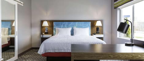 Ein Hotelzimmer mit einem großen Bett, zwei Nachttischen mit Lampen, einem Holztisch und einem Stuhl.