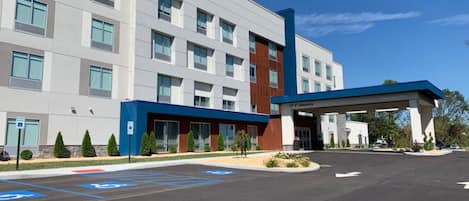 A Hampton Inn & Suites hotel with a modern facade, a covered entrance, and designated handicapped parking spaces.