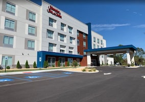Un hotel Hampton Inn & Suites con fachada moderna, acceso cubierto y espacios de estacionamiento reservados para discapacitados.