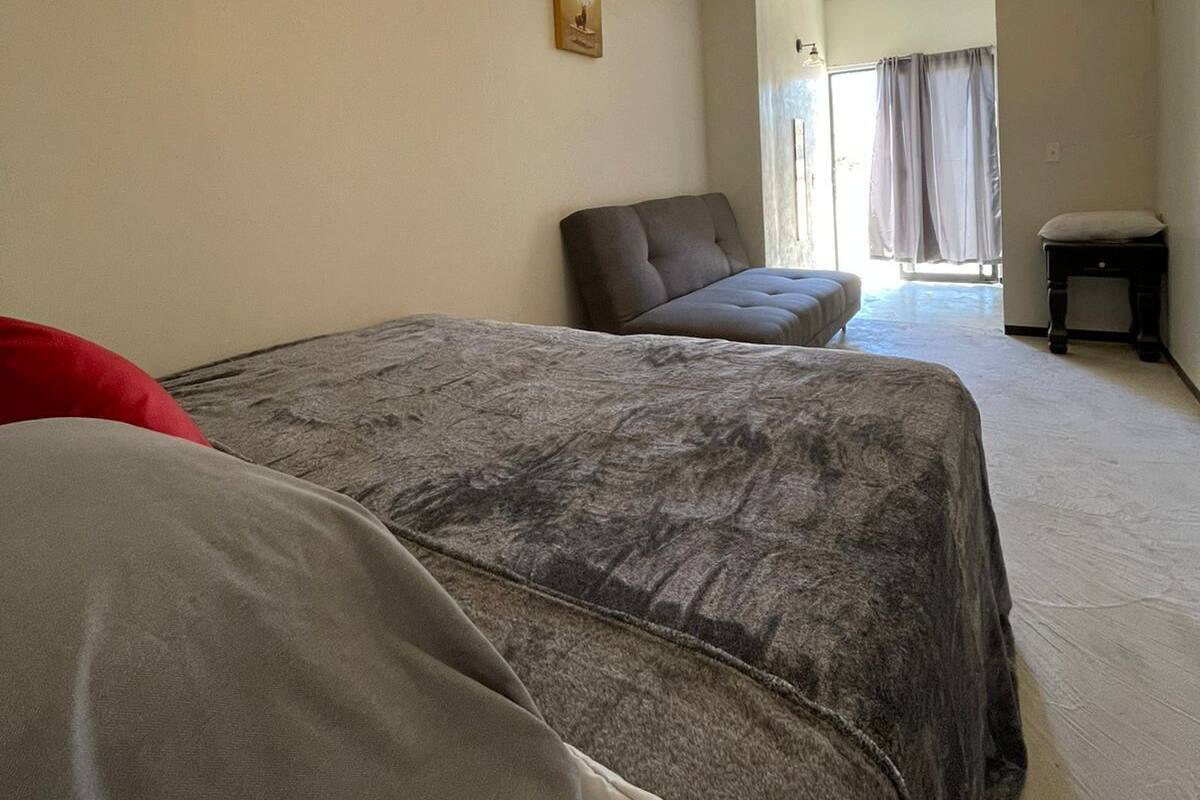 A room with two beds, a sofa, a small table, and a painting on the wall.
