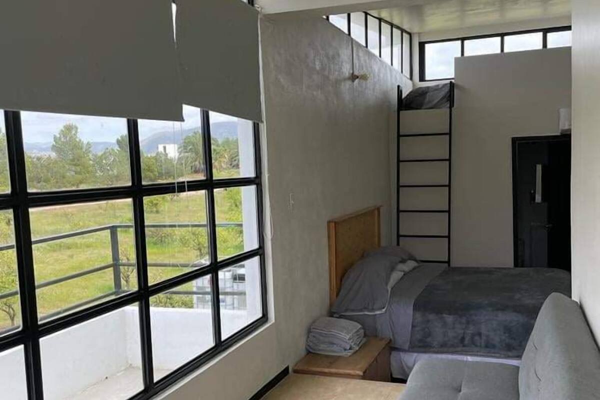 A bedroom with a large window, a bunk bed, and a sofa.